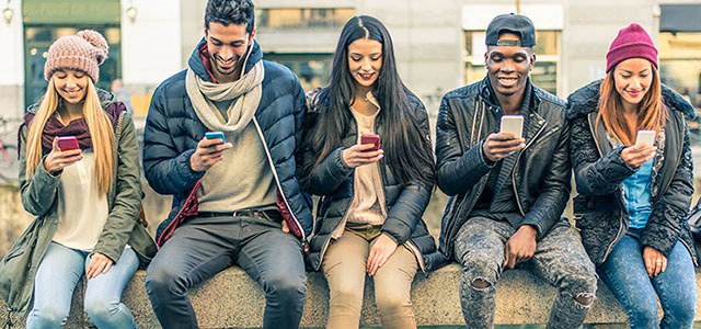 Group of high school kids sitting on a way with mobile phones